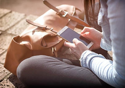 woman looking at cellphone sitting on sidewalk